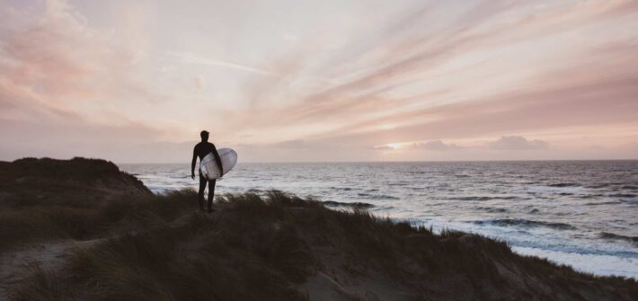 En person som står med sit surfboard log skuer over havet