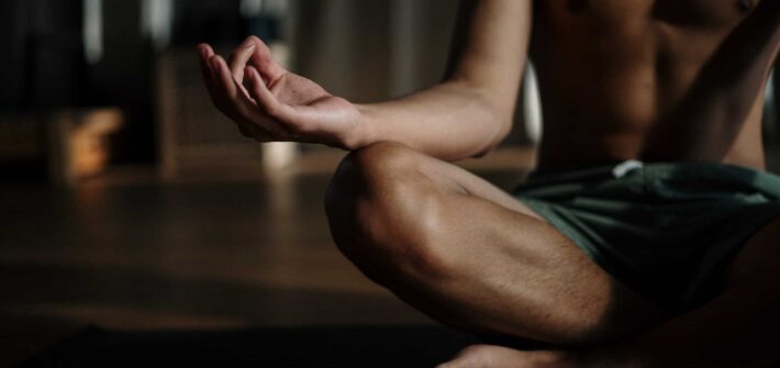 Et billede af en mand der mediterer, hvor man kan se venstre del af kroppen